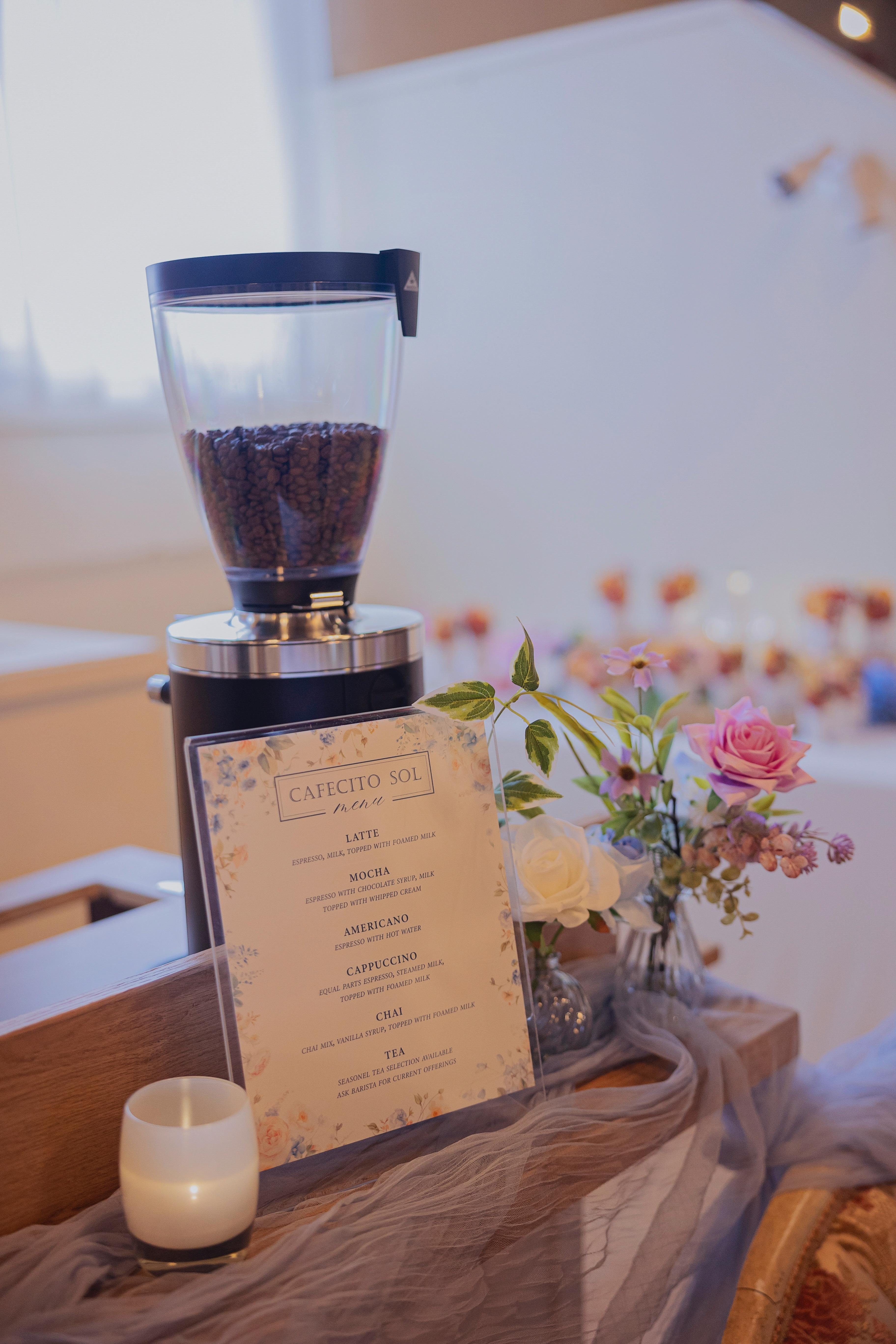 A Cafecito Sol drink menu displayed beside flowers at a wedding coffee bar
