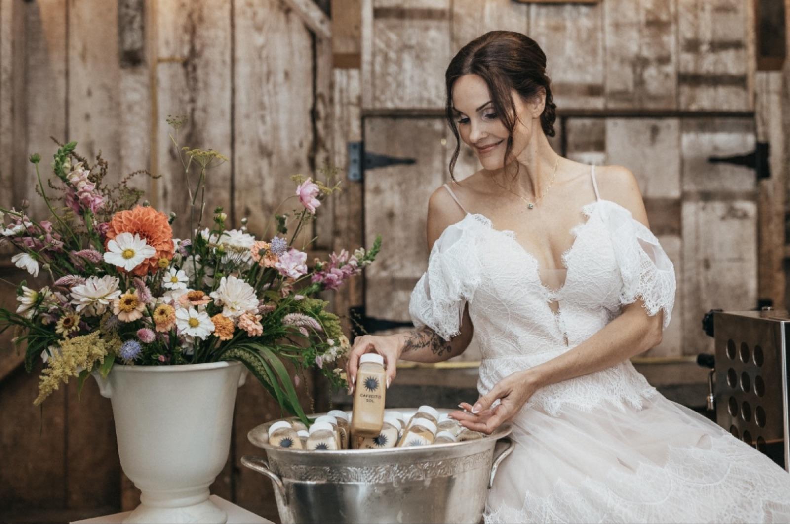 A bride reaching for a bottled Cafecito Sol drink chilling in a silver bucket