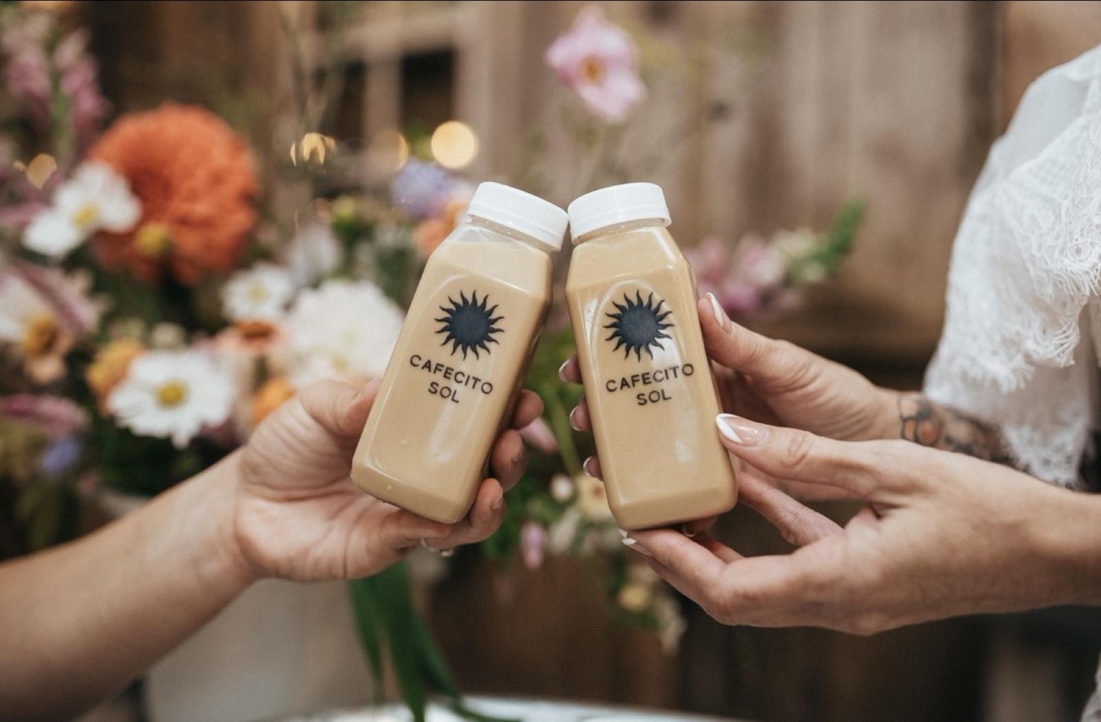 Two guests toasting with bottled Cafecito Sol coffee drinks